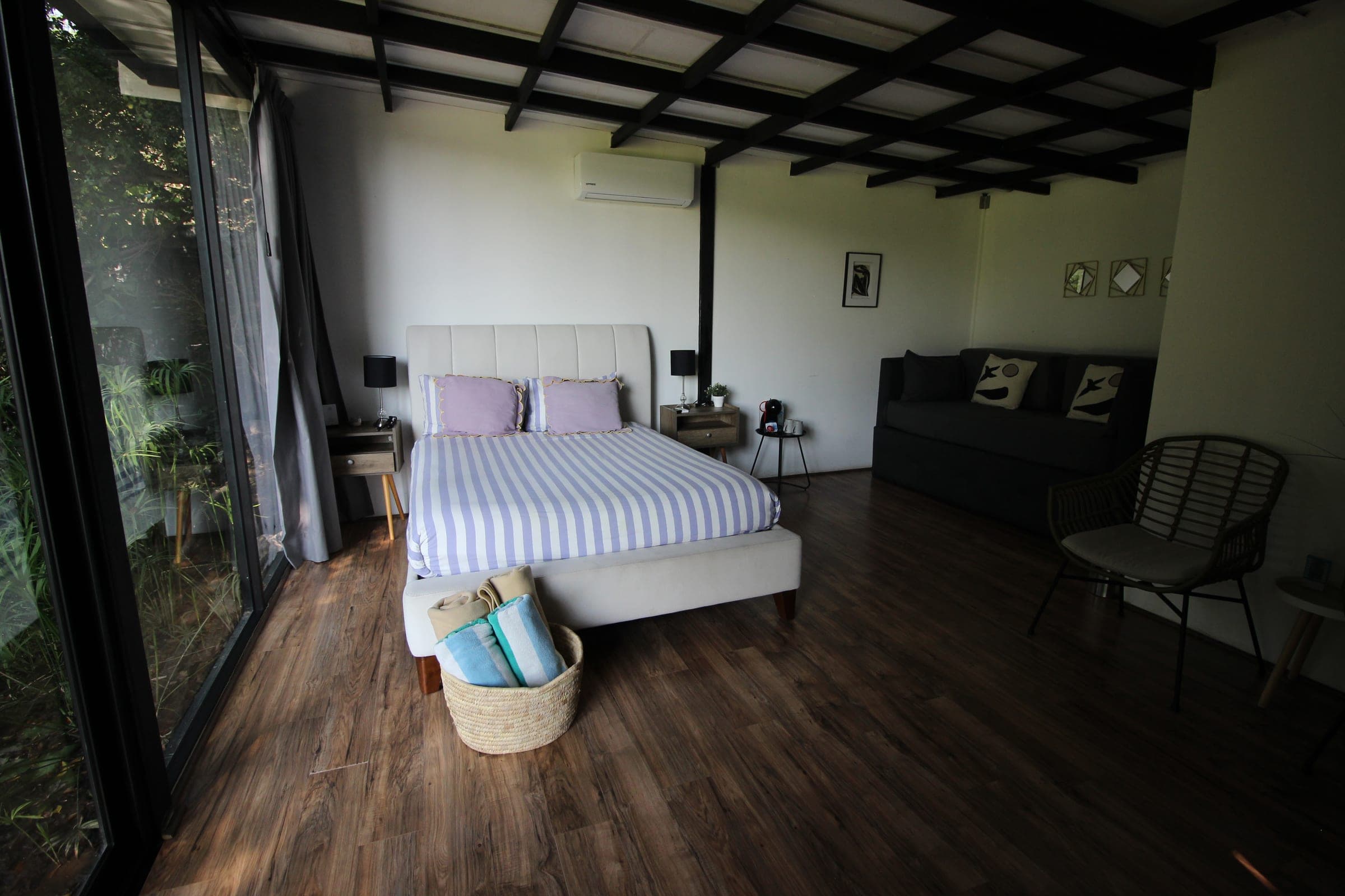 Cama con ropa de cama a rayas lila y blanco, con mesas de noche a ambos lados