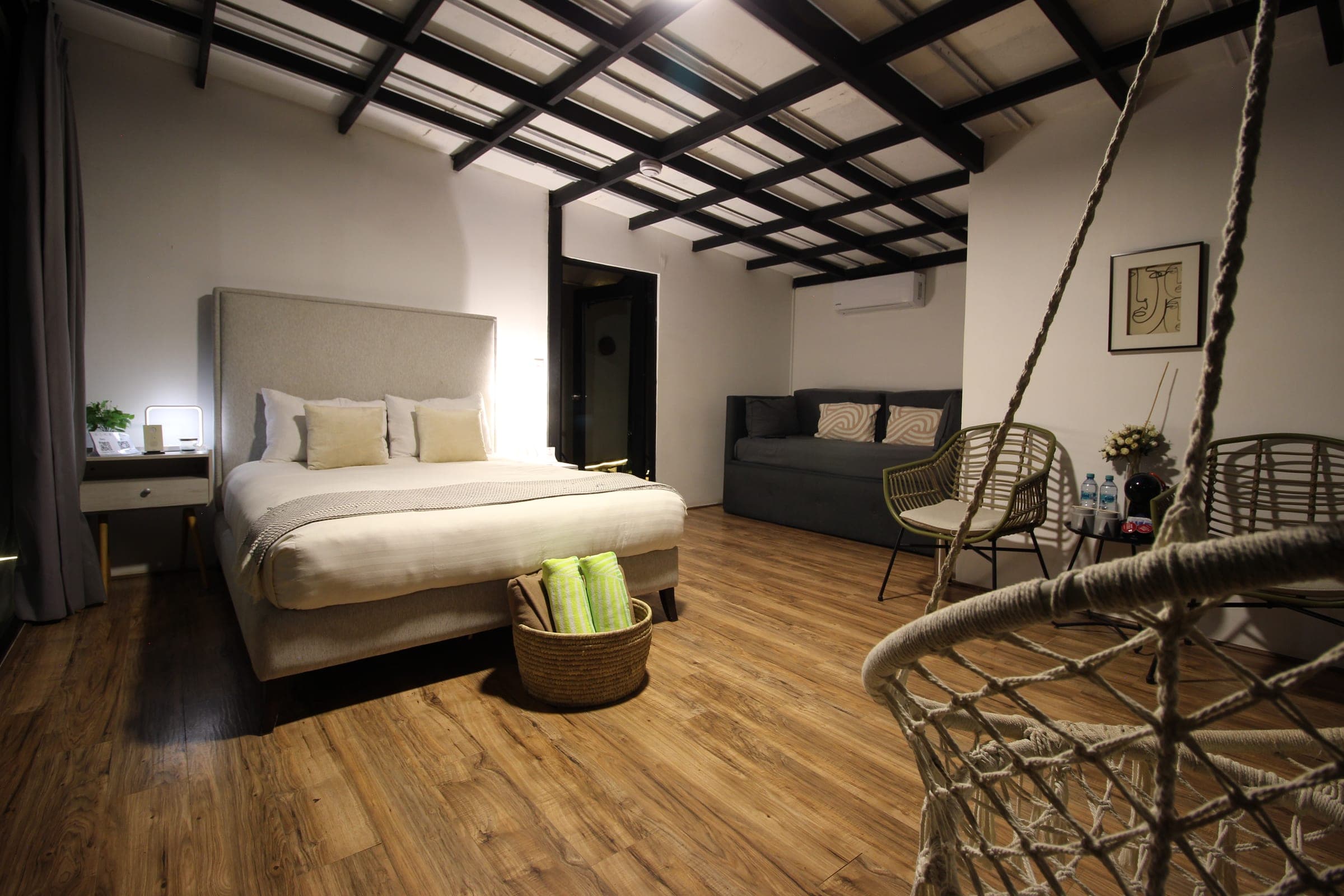 Vista panorámica de la habitación con la cama, la sala de estar y la silla colgante de mimbre