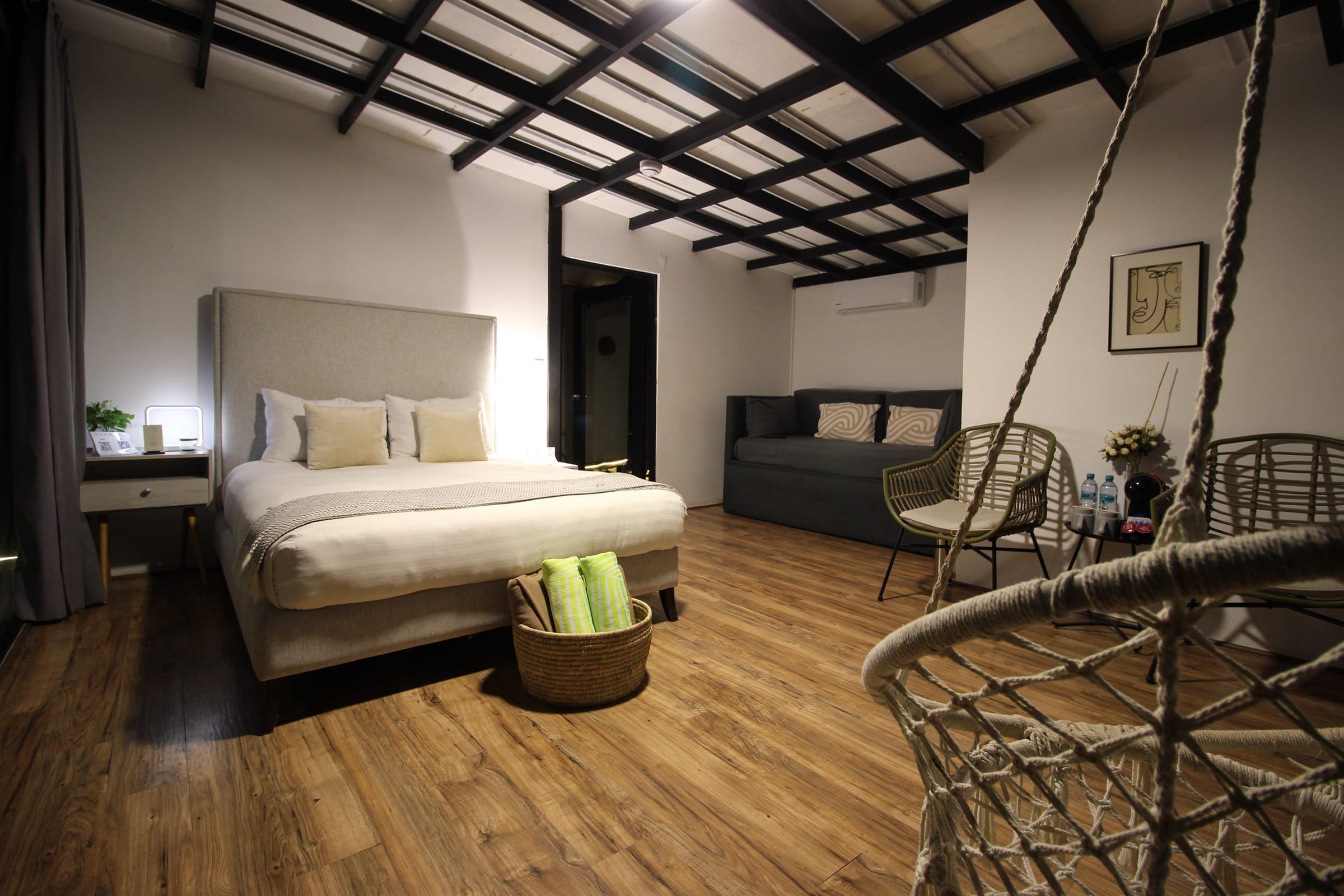 Interior nocturno con cama, sofá cama y silla colgante de macramé